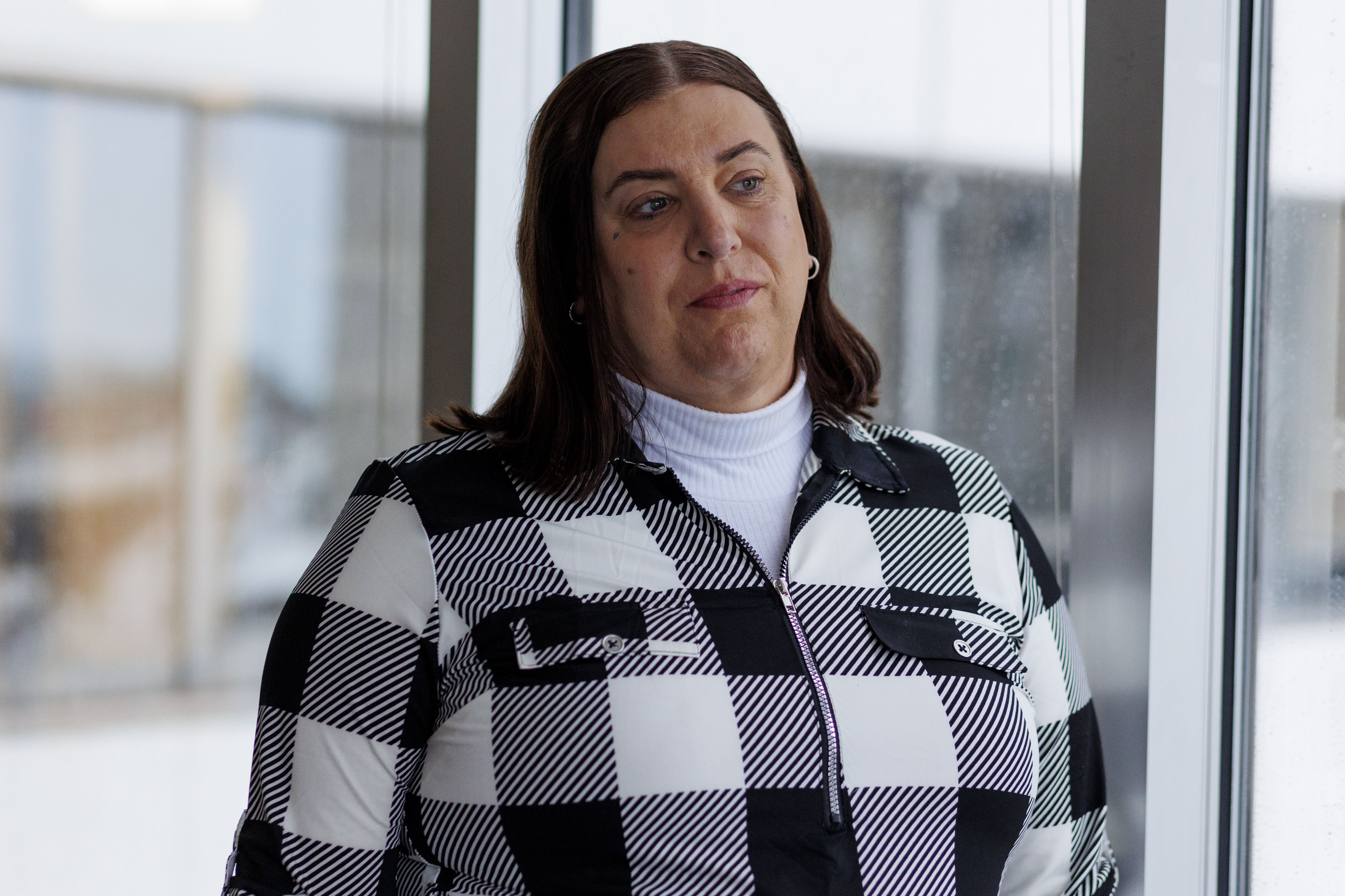 A portrait of a middle-aged woman with straight brown hair wearing a black-and-white checkered jacket.