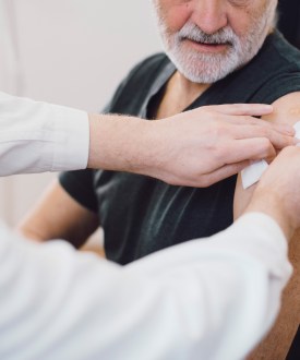A photo of an older man having his arm bandaged after getting a vaccine.