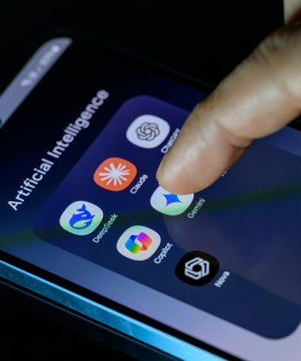 A photo of someone's smartphone with a folder full of AI apps: DeepSeek, Claude, ChatGPT, Copilot, Gemini, AI Photo, and Nova.