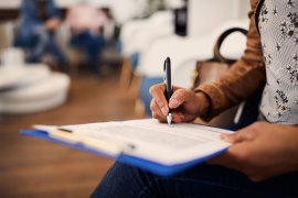 A photo of a woman in a medical office filling out a form.