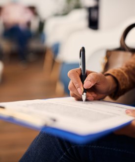 A photo of a woman in a medical office filling out a form.