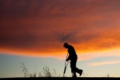 A silhouette of an injured senior man with crutches.