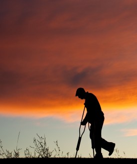 A silhouette of an injured senior man with crutches.