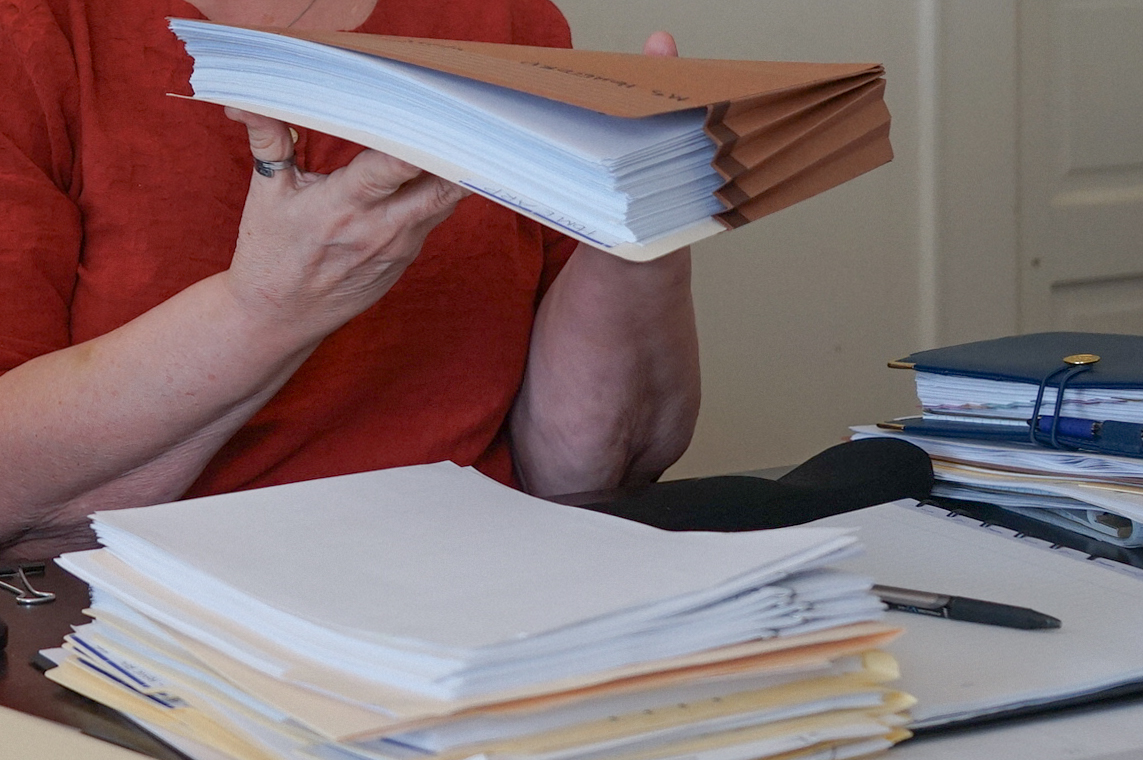 An unidentifiable person holds up a thick stack of paperwork.