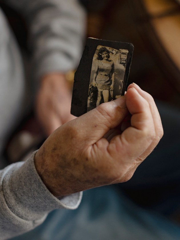 A hand holding a black-and-white photo of a woman