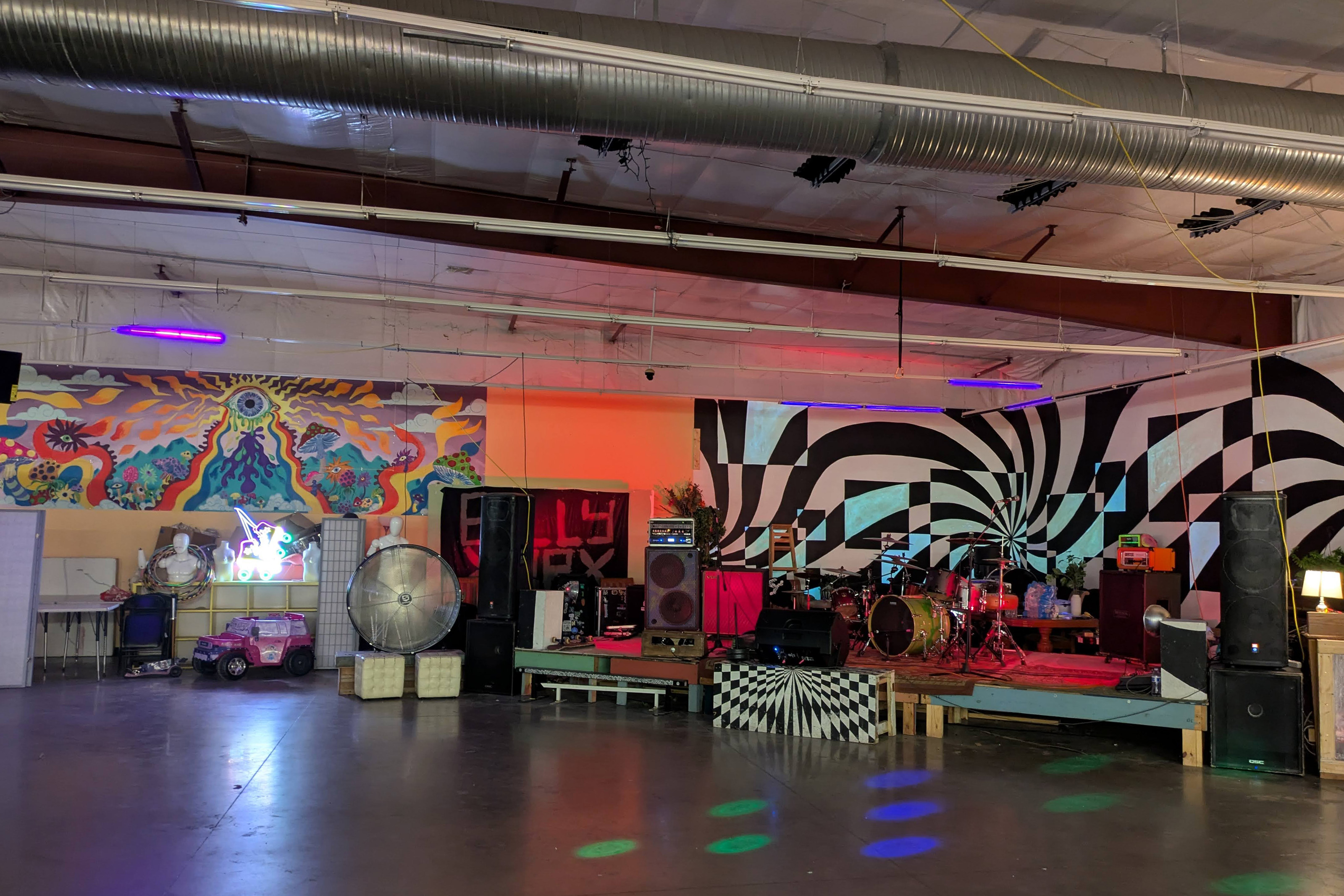 A photo of a small concert space with a drum set on stage.