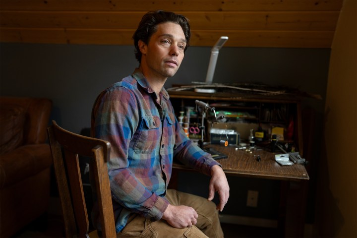 A photo of a man sitting at a desk indoors.