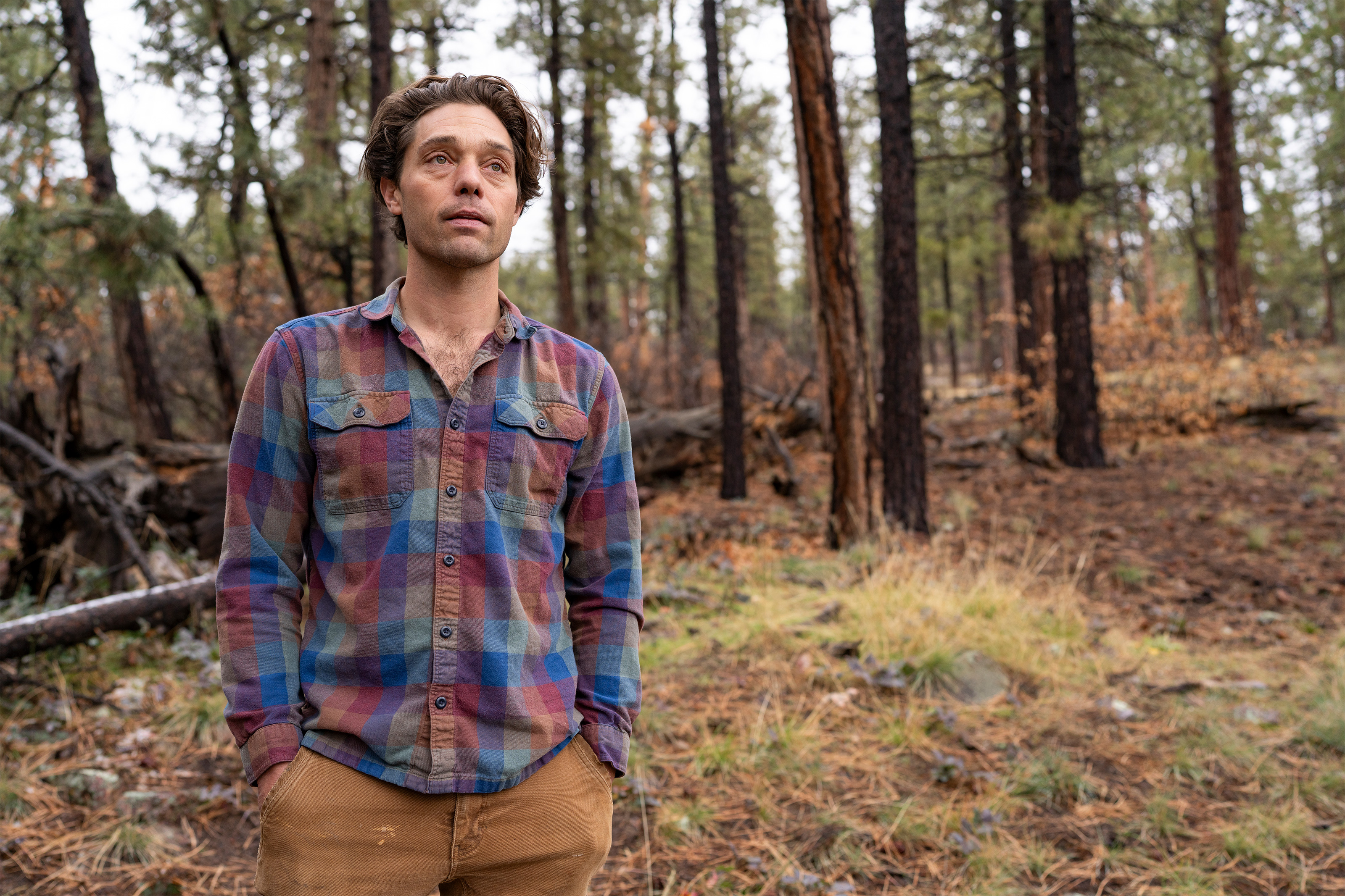 A photo of Kruzic posing for a photo outside by a wooded area.