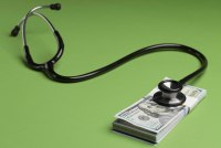 A photo of a stethoscope against a green background. It is resting on top of a stack of $100 bills.