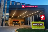 An exterior photograph of an emergency entrance at a hospital at daybreak.