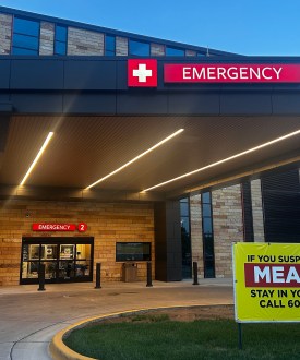 An exterior photograph of an emergency entrance at a hospital at daybreak.