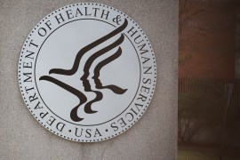 The emblem of the Department of Health & Human Services is shown on the side of a building