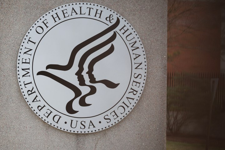 The emblem of the Department of Health & Human Services is shown on the side of a building