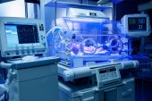 A baby lies in an incubator in a neonatal intensive care unit.