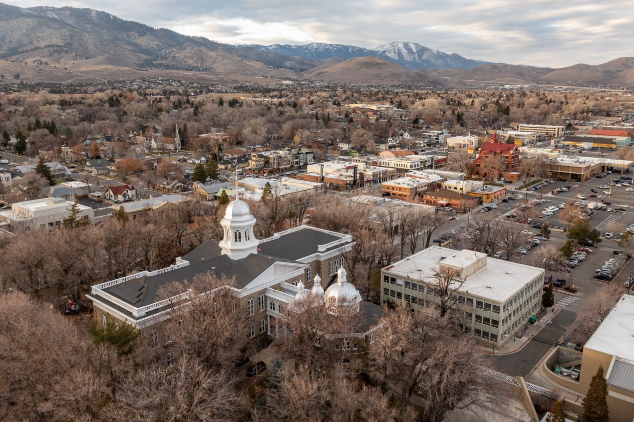 Aerial view of buildings in a city with foothills and mountains in the background