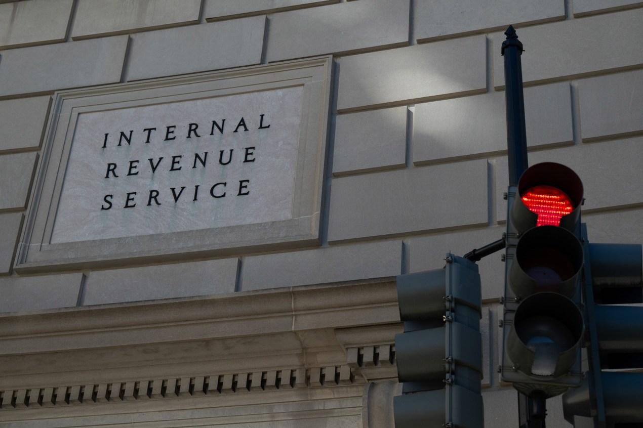 Photo of the exterior of a stone building with a sign that says "Internal Revenue Service" along with a traffic light next to it