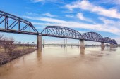 A view of a bridge crossing a muddy river with another bridge in the background