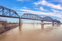 A view of a bridge crossing a muddy river with another bridge in the background