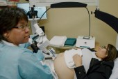 A pregnant woman is laying down for an ultra sound from a robotic ultrasound machine