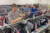 Two men sort racks of clothes in a Goodwill store.