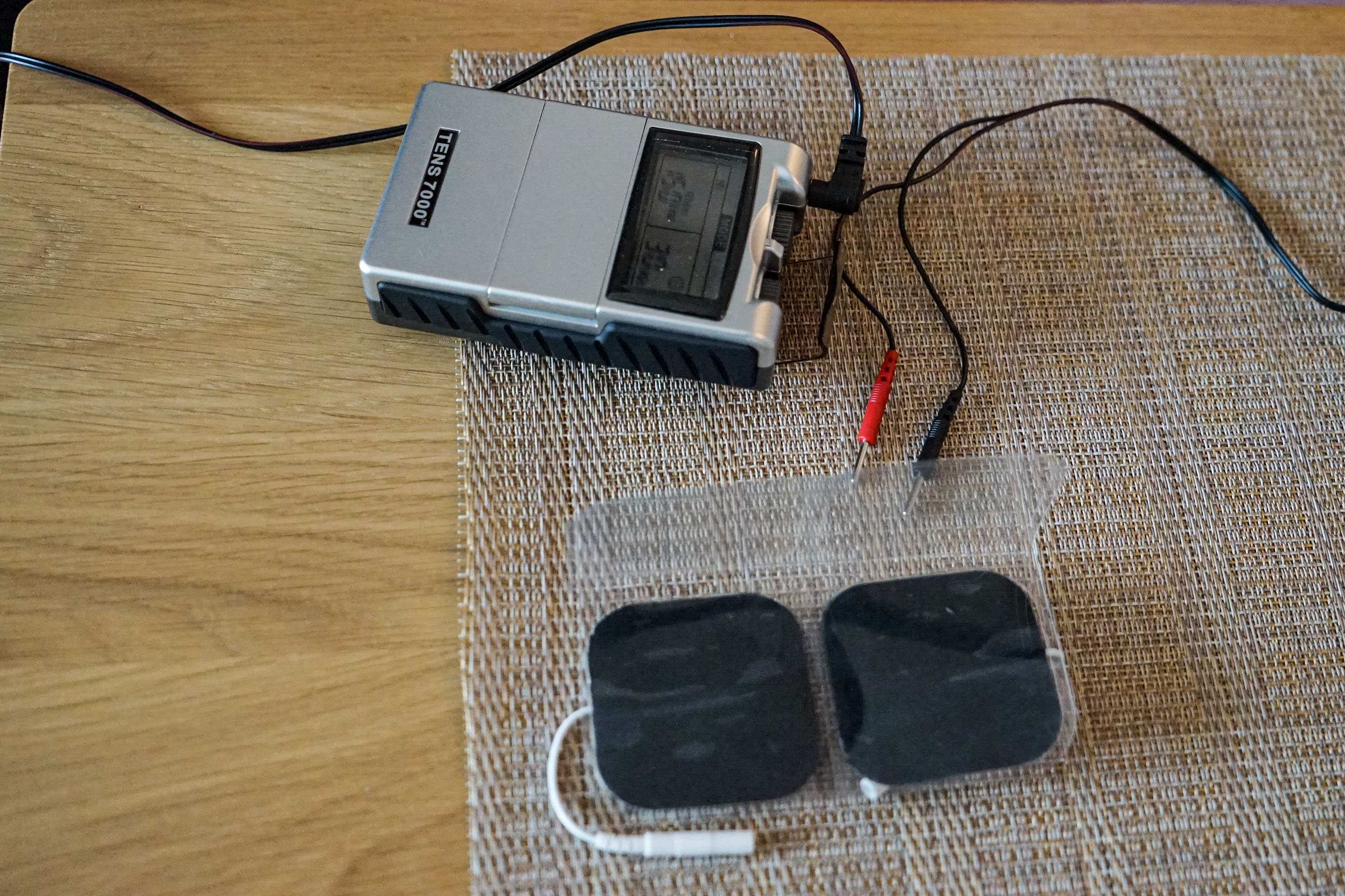 A small medical device rests on a wooden table.