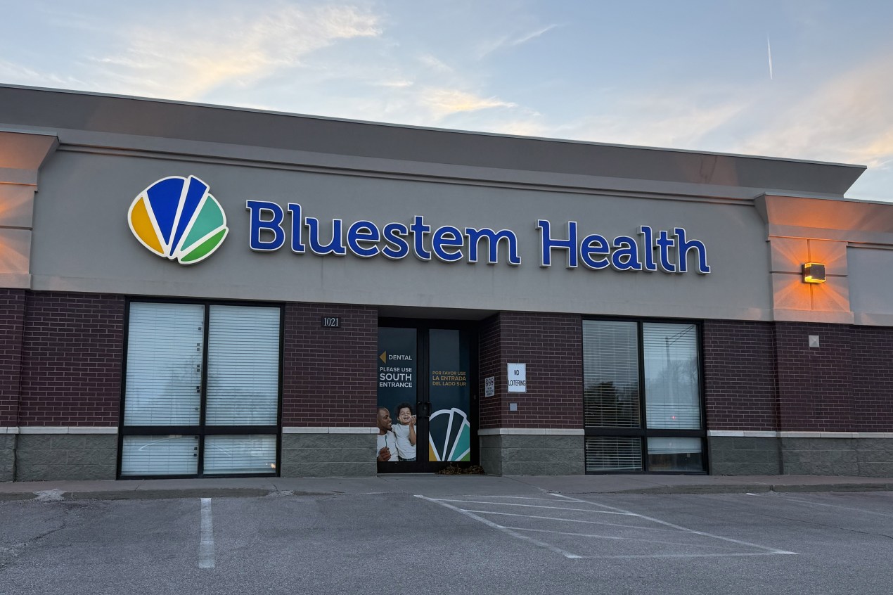 An exterior of a health clinic with a blue sign that reads, "Bluestem Health."
