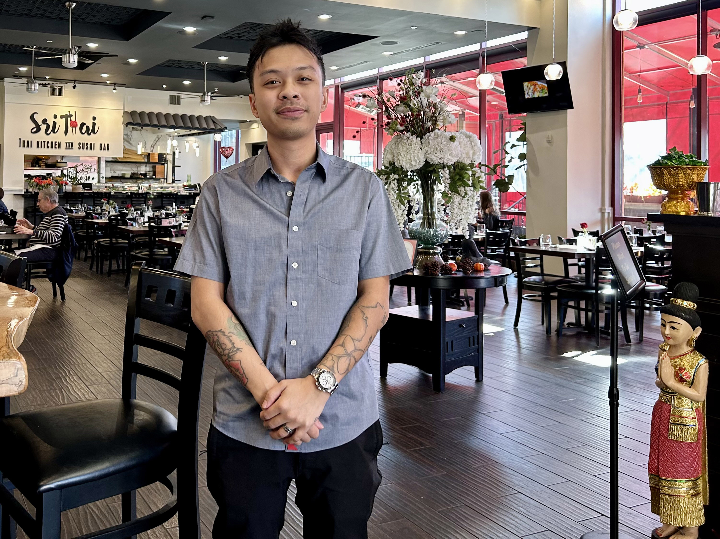 A man stands for a portrait inside a Thai restaurant dining room