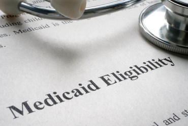 A sheet of paper says "Medicaid Eligibility" with a stethoscope resting on top.