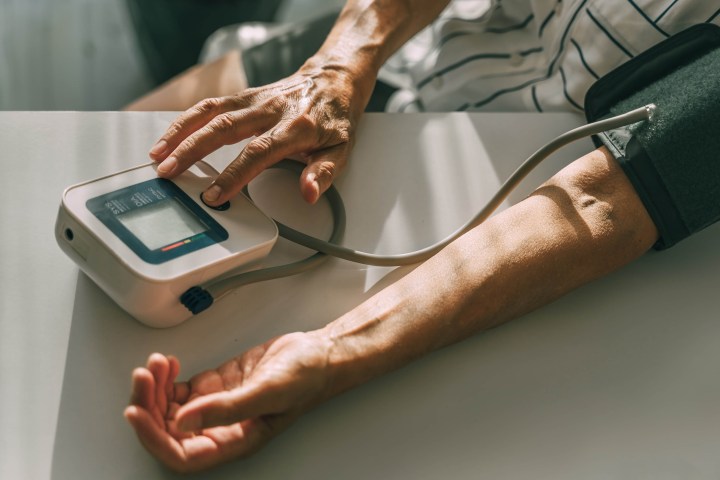 An elderly woman takes her blood pressure at home. Unrecognizable person, hand close-up.