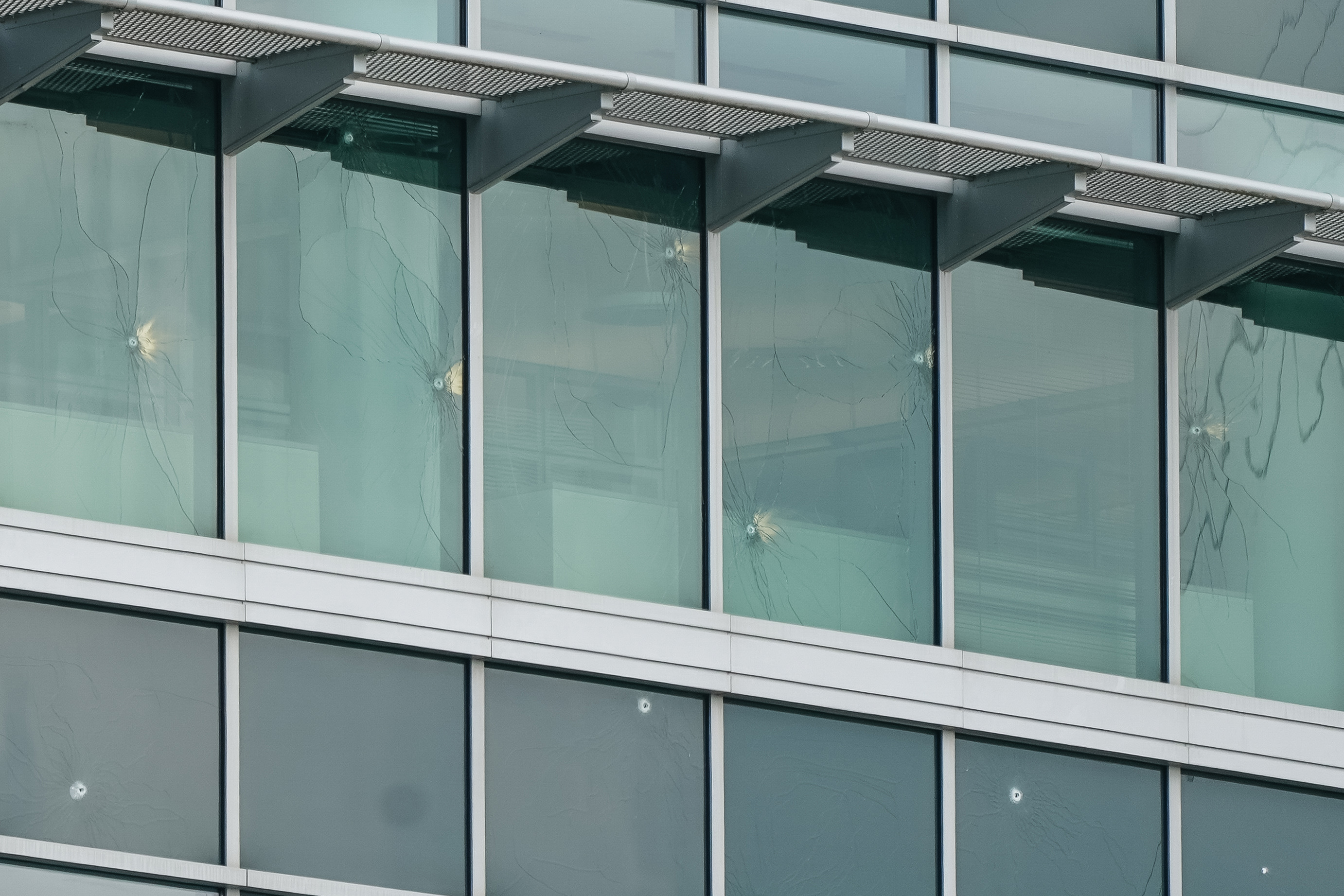 Bullet holes are seeing in the windows of an office building