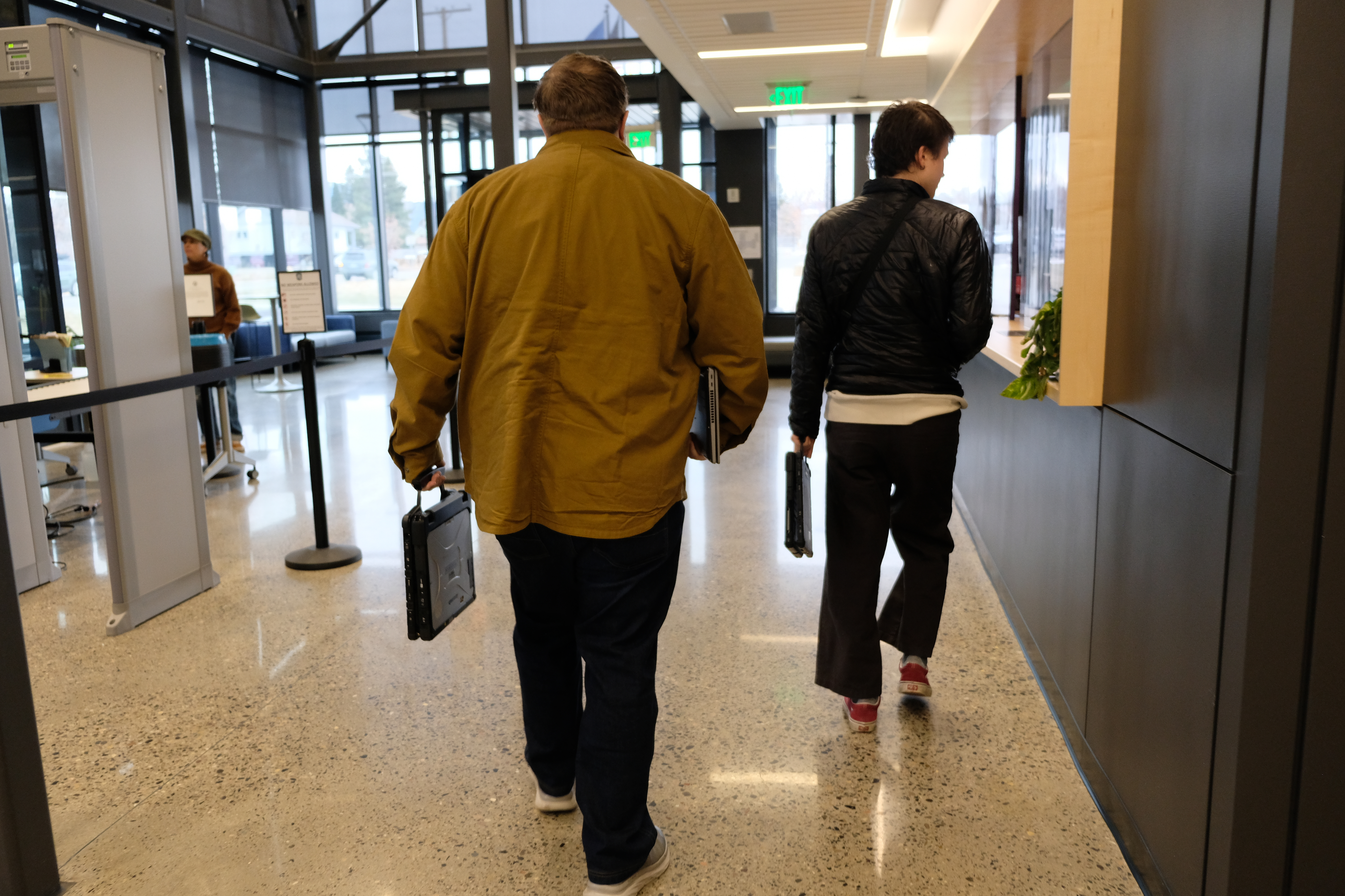 A shot of the backs of two men, one in a khaki jacket, the other in a leather jacket