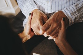 A woman holds the hands of a senior man.