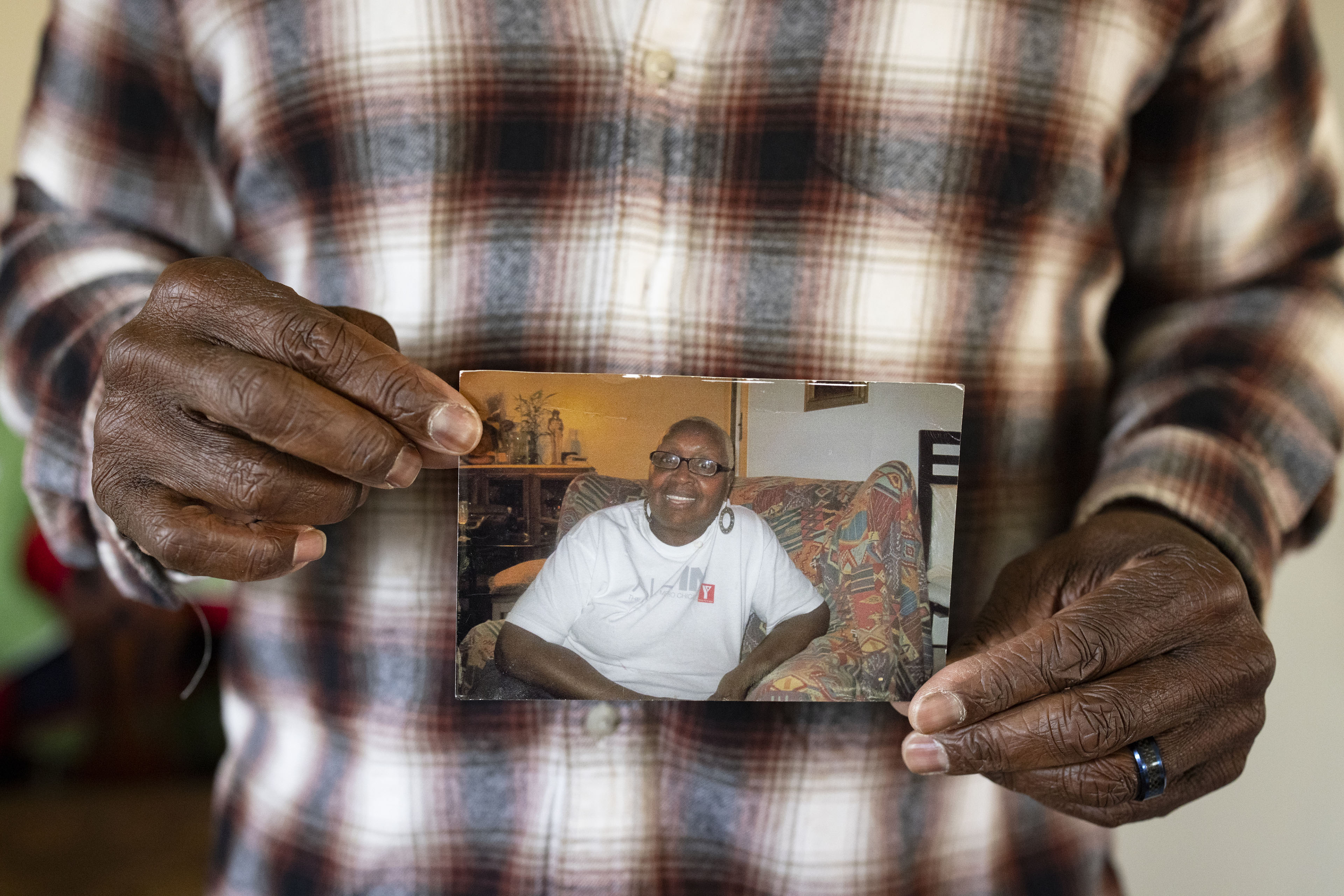 A man holds a paper photograph of a woman in his hands for a photo
