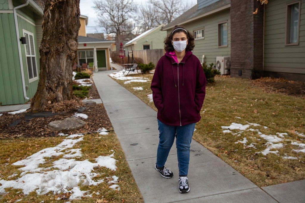 Suzan Mubarak stands outside, wearing a face mask