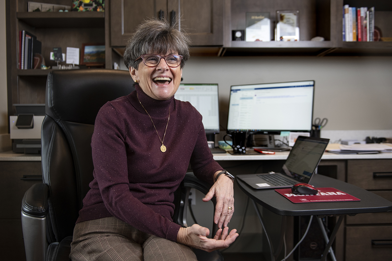 Photo of Marilyn Bartlett sitting at her desk smiling