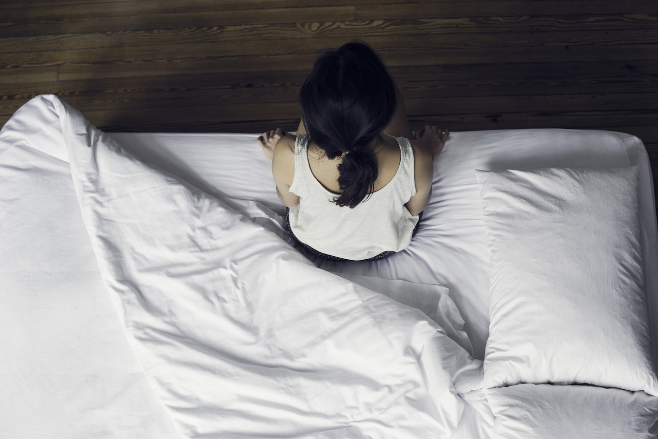 Woman sitting on edge of bed waking up