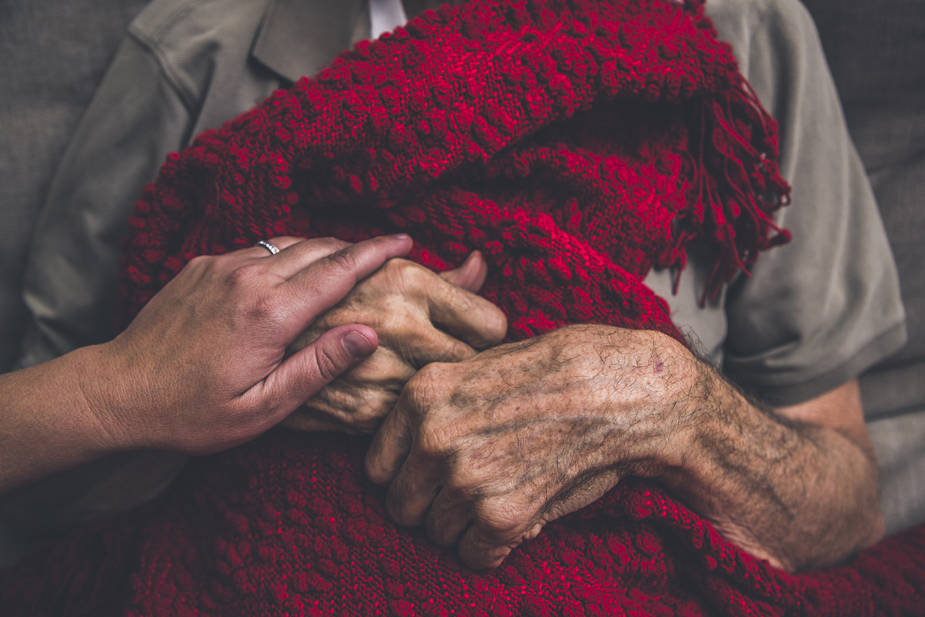 Someone holds the hand of a frail senior