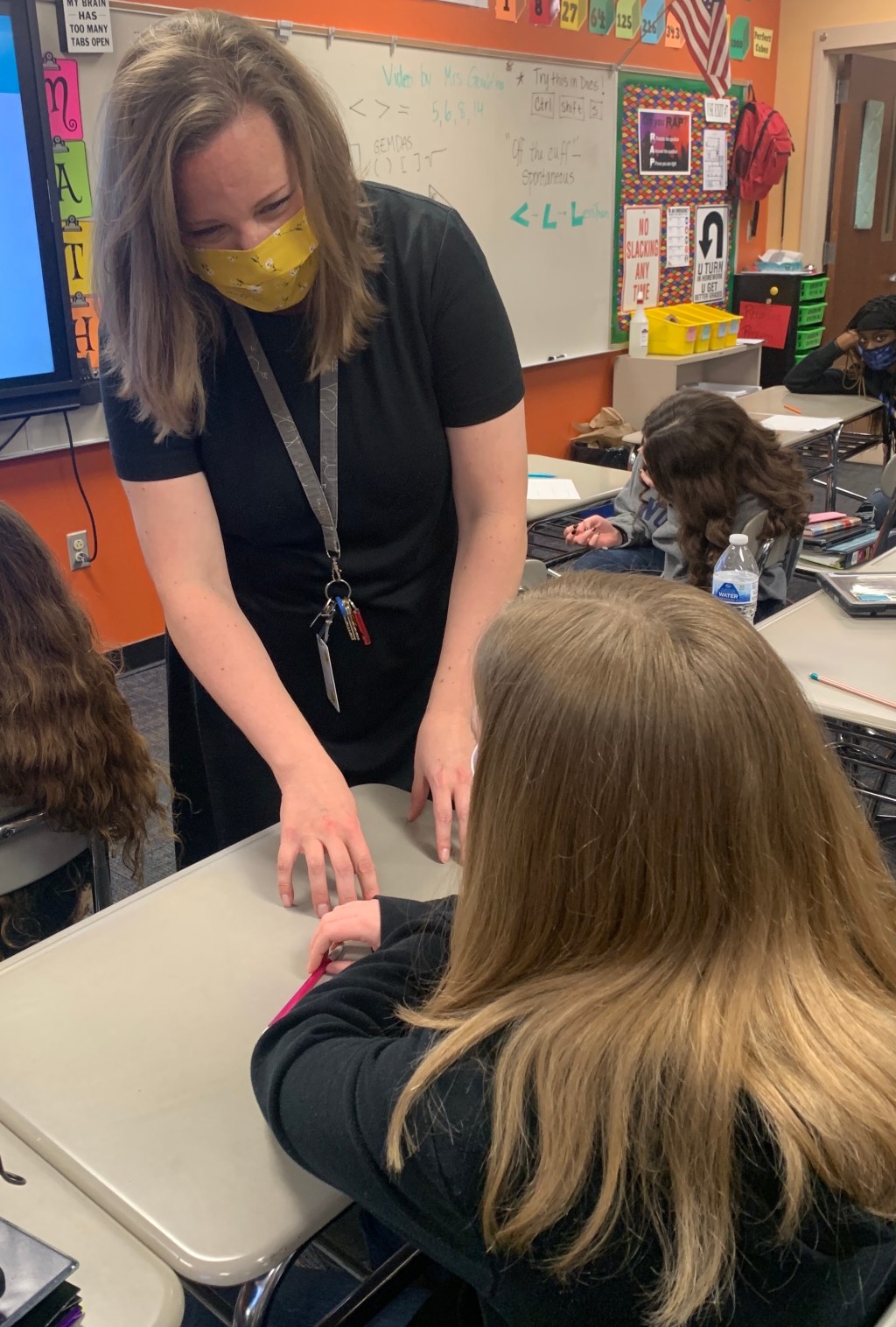 teacher wearing mask instructs seated child