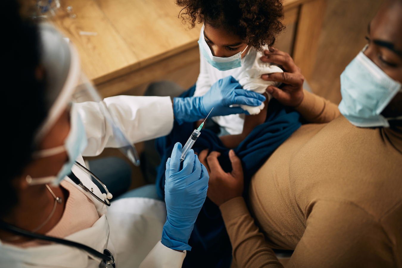 Close-up of doctor vaccinating African American girl during coronavirus pandemic.