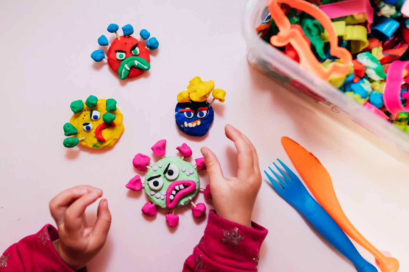Child playing with plasticine at home making virus