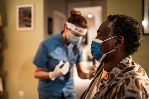 A health worker prepares to give a senior man a shot.