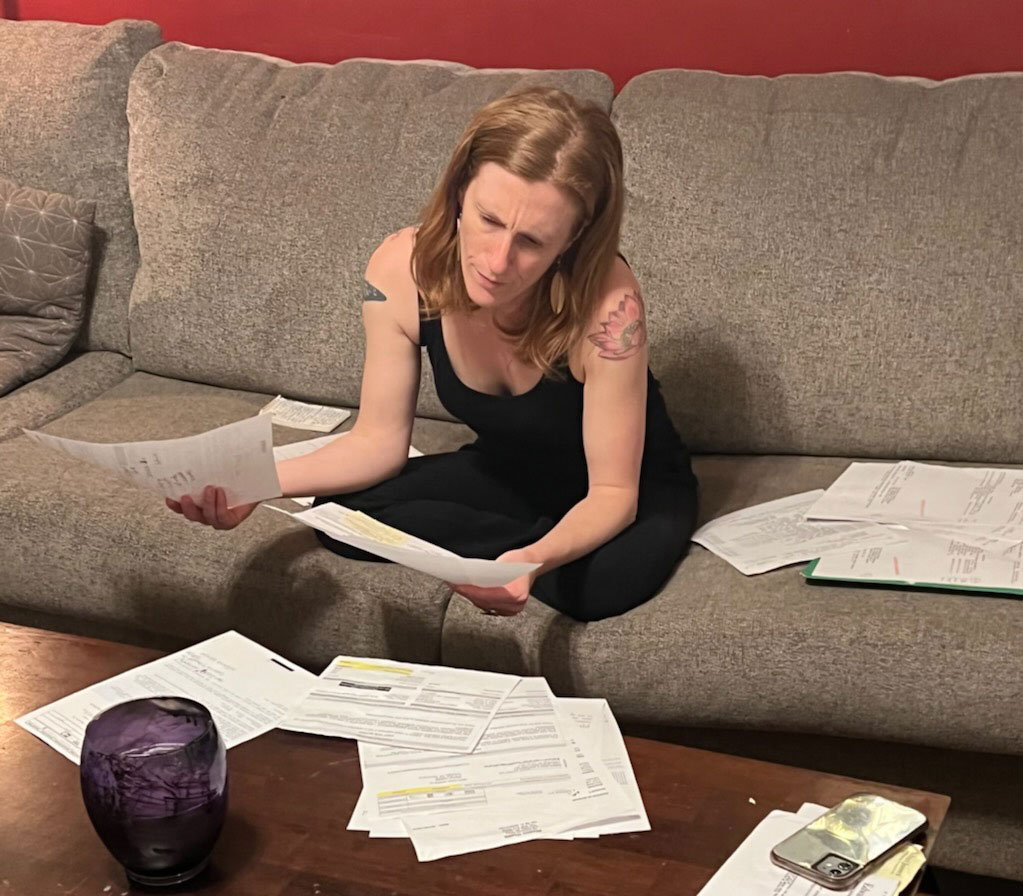 A woman sit on a couch and looks at papers.