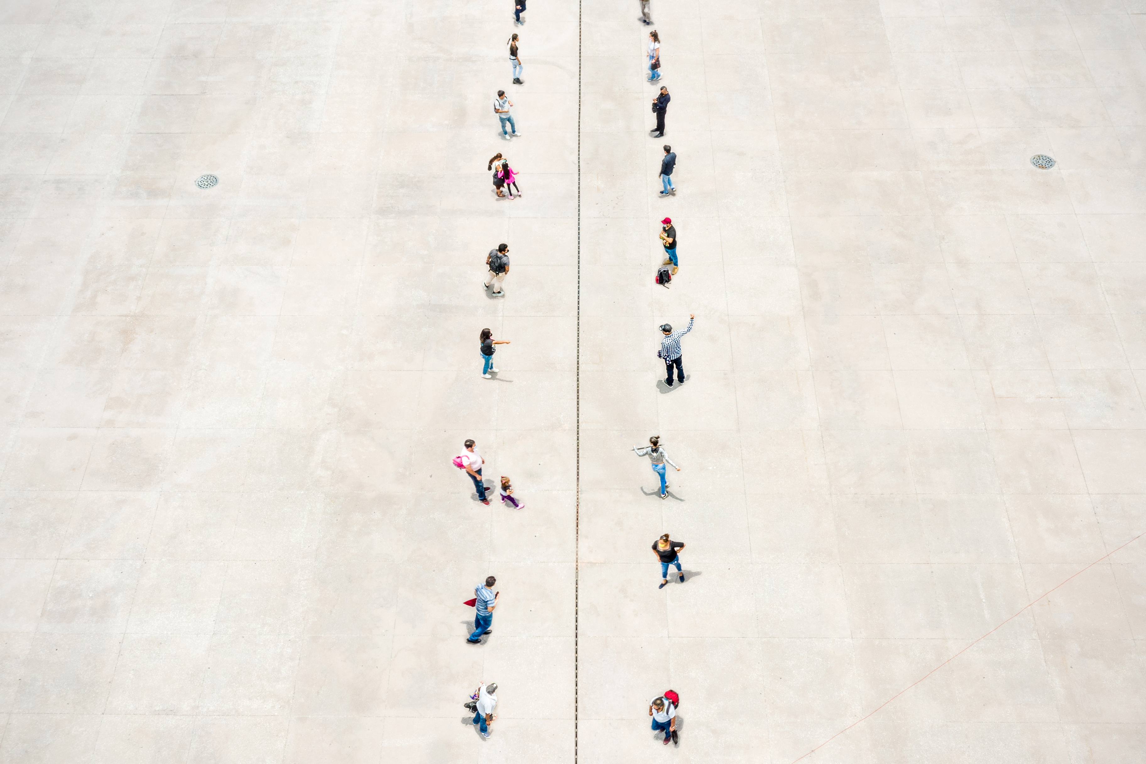 A photo illustration shows two rows of people standing on separated zones, divided in the middle with a dashed line.