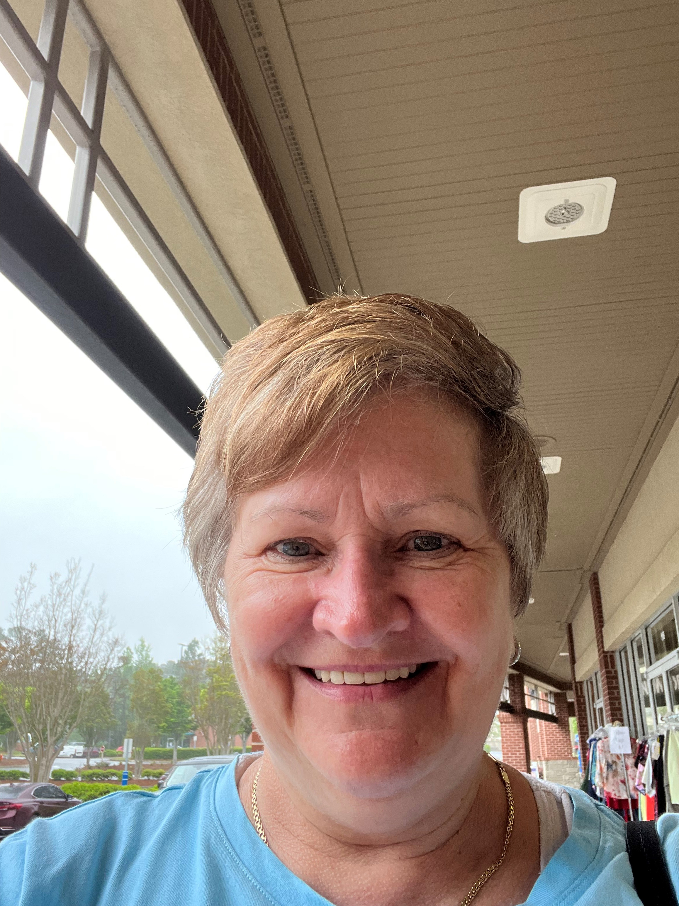 Tina Passione smiles while taking a selfie outdoors.