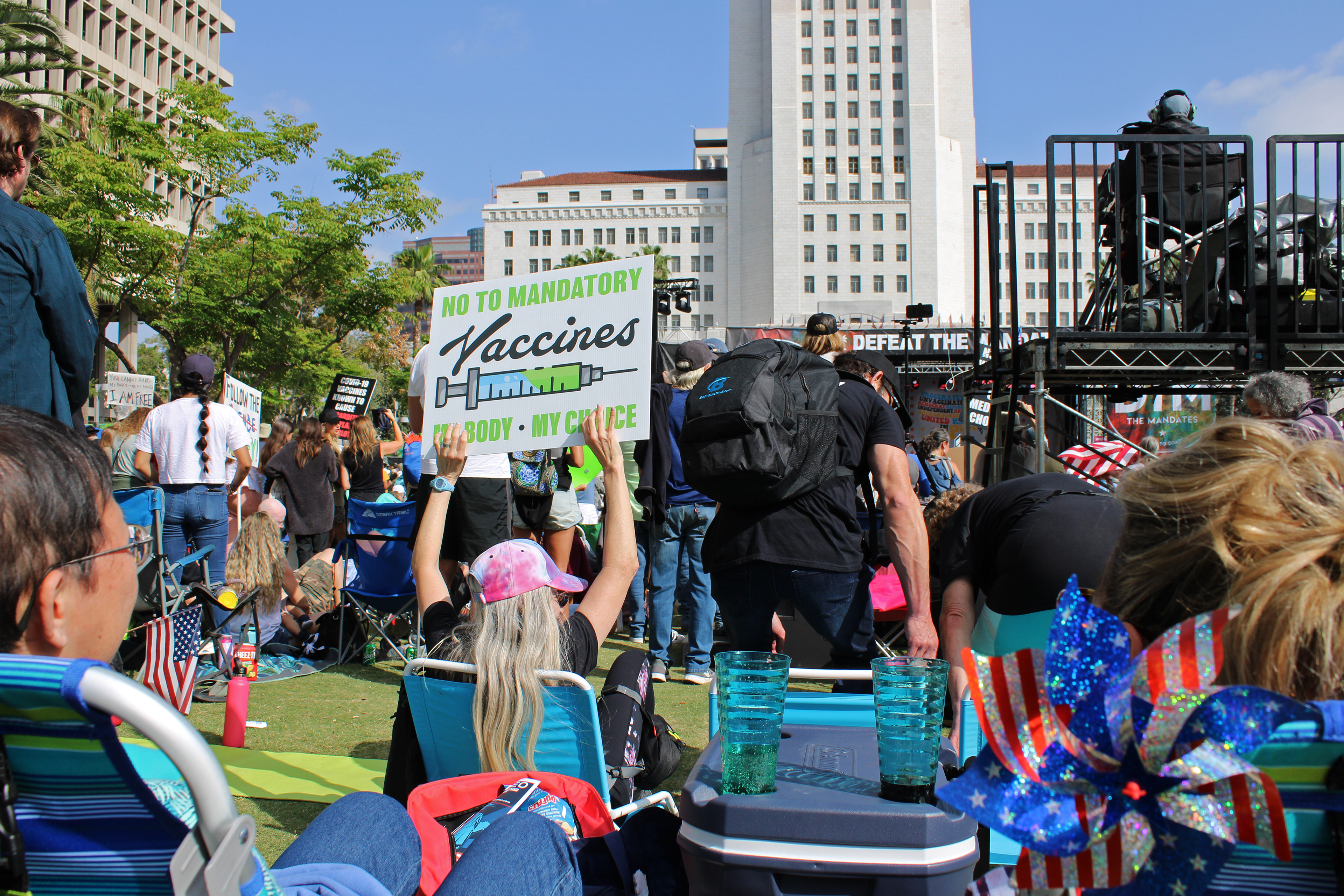 A photo shows a crowd of protesters. One woman holds up a sign that reads, "No to mandatory vaccines. My body, my choice."