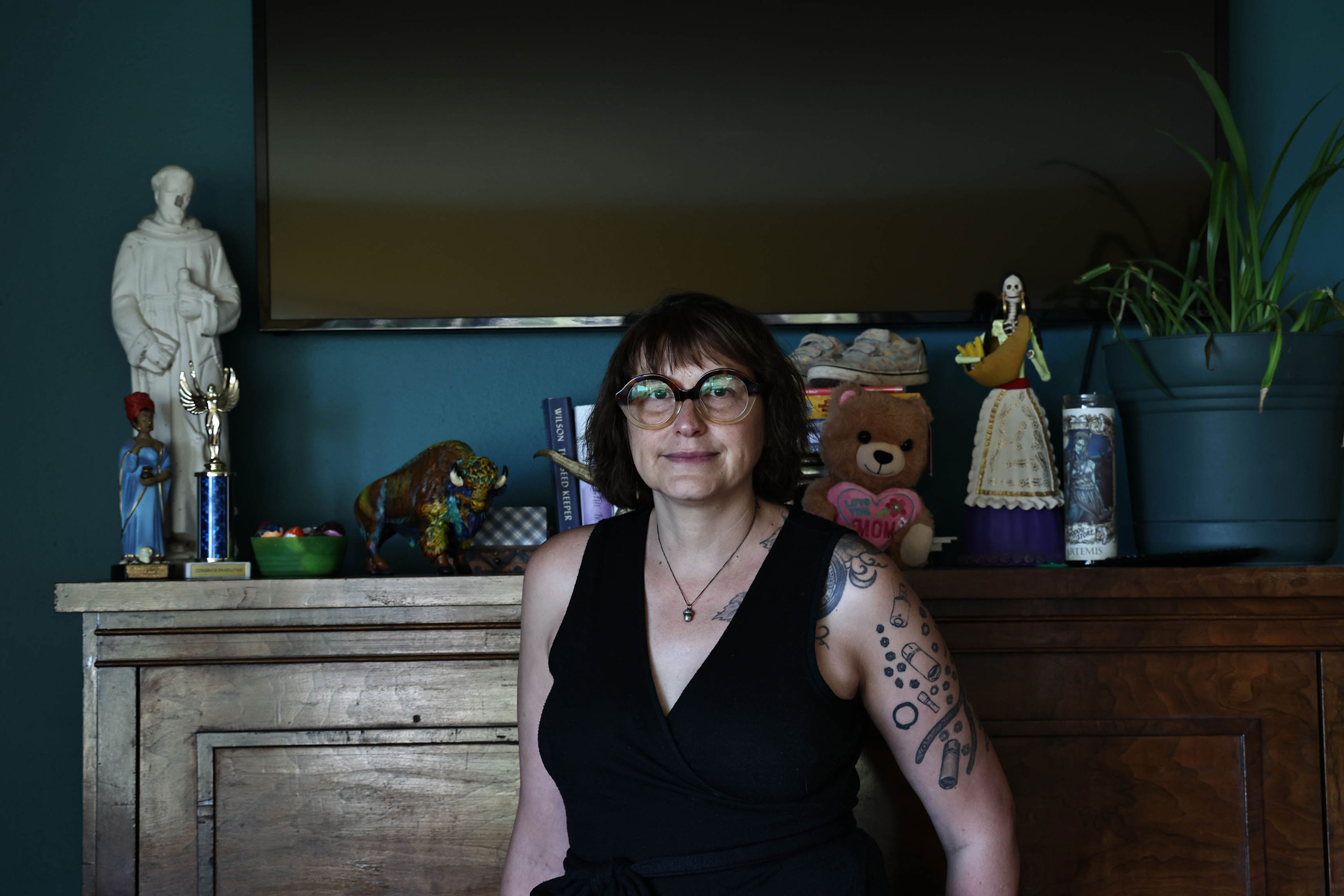 A woman stands in front of a display shelf and television mounted to the wall above it.