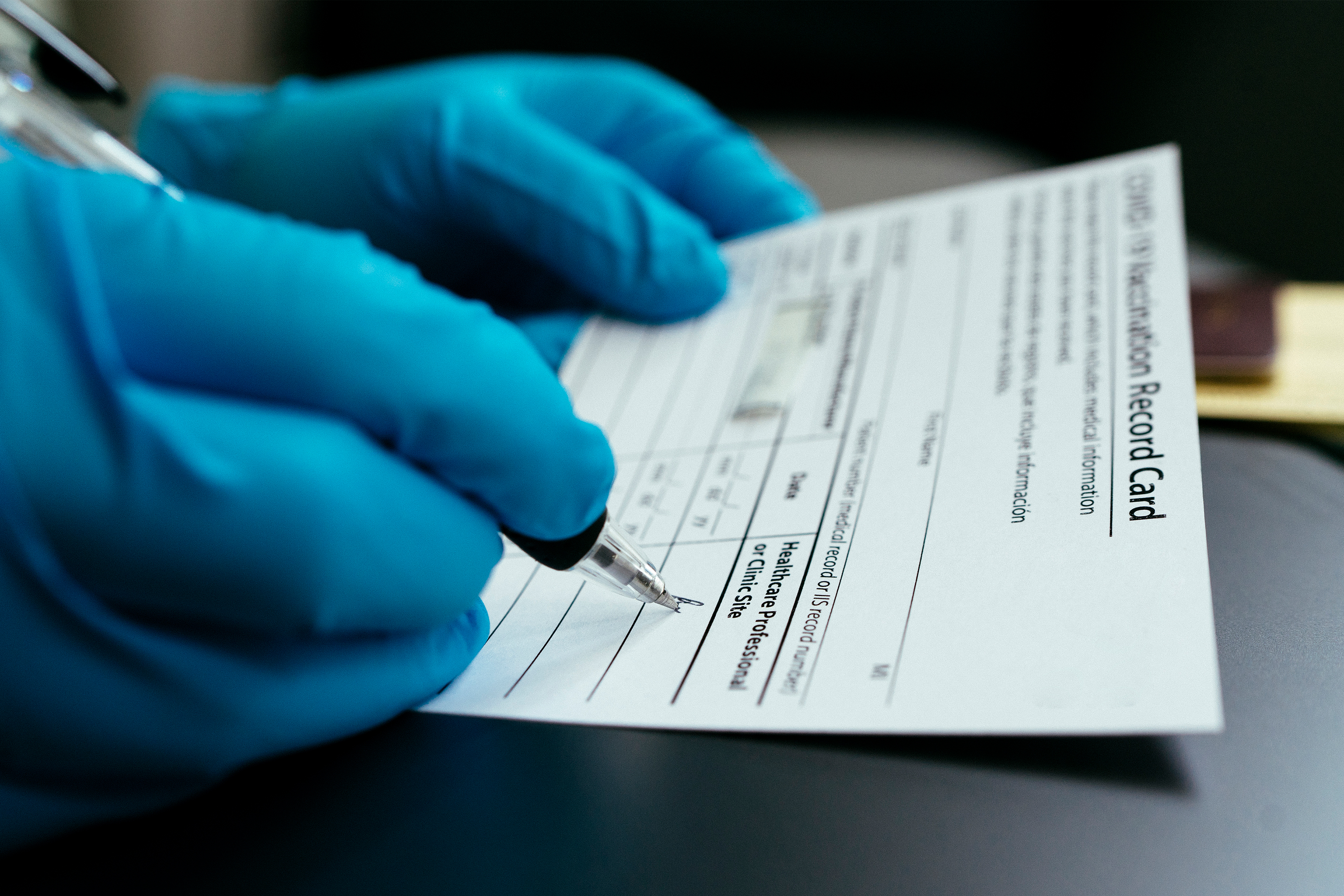 A photo shows a medical professional signing a covid vaccine card.