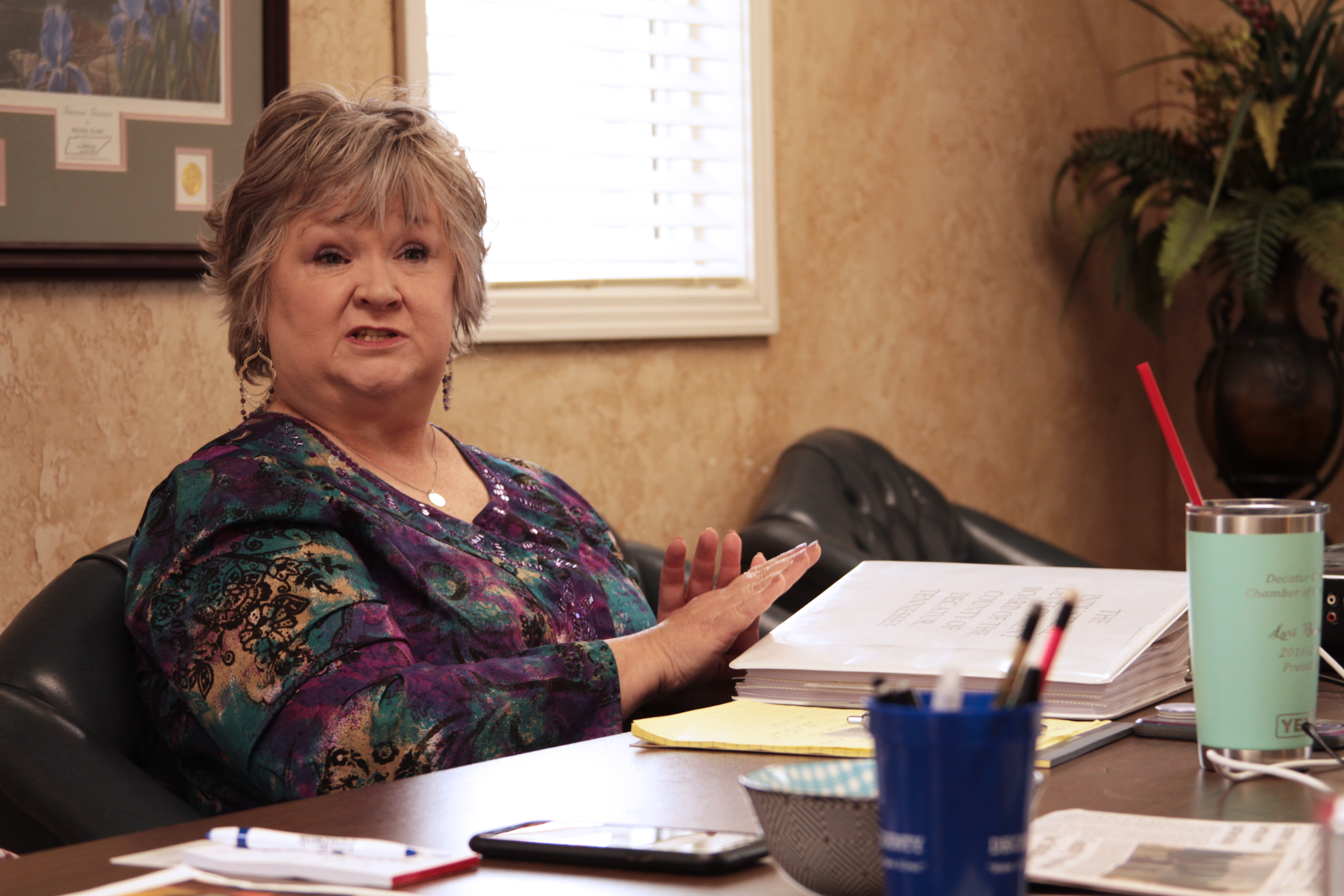 A photo shows Lori Brasher speaking to someone out of frame at a table.