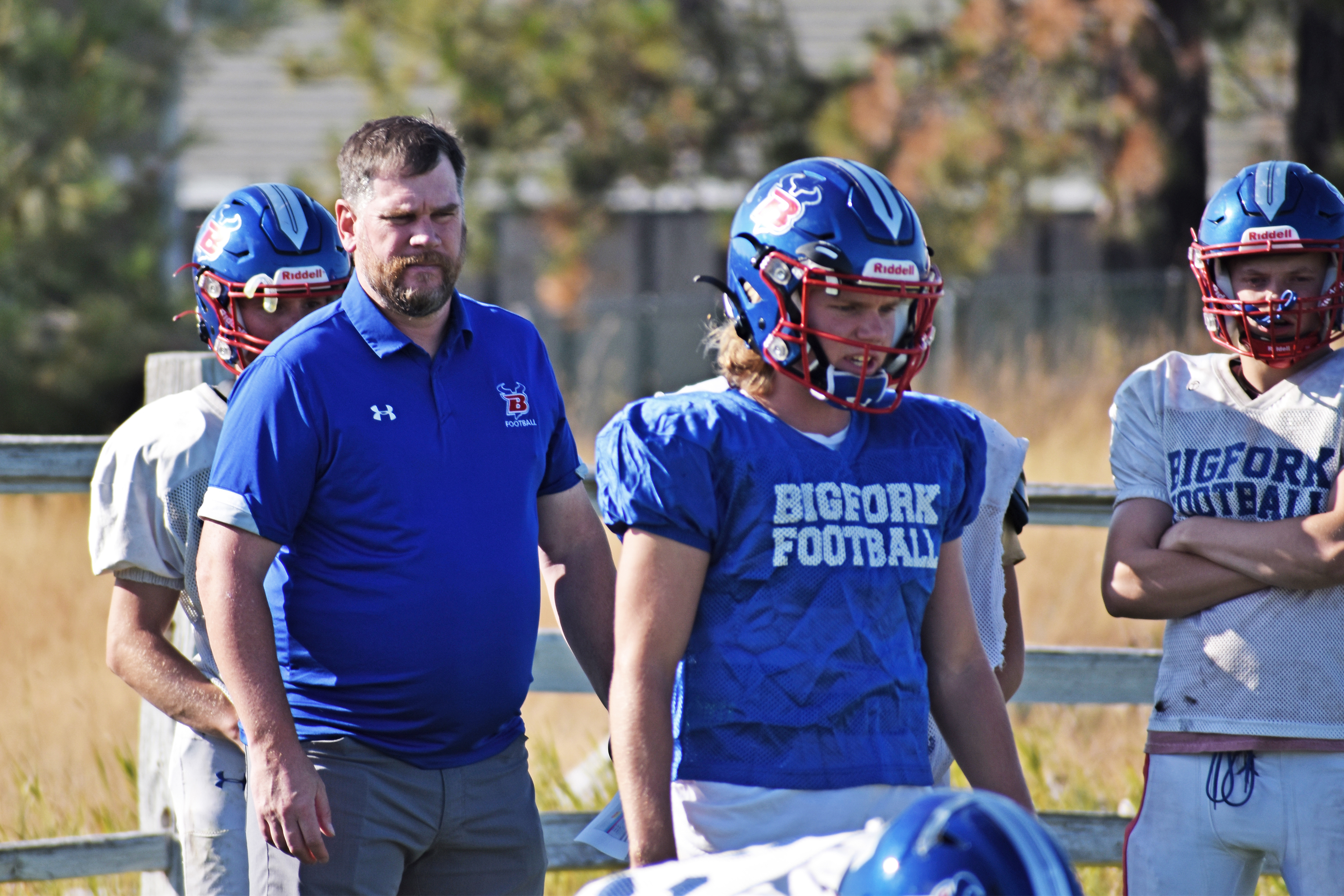 A photo shows Jim Benn outside and surrounded by members of the Bigfork Vikings football team.