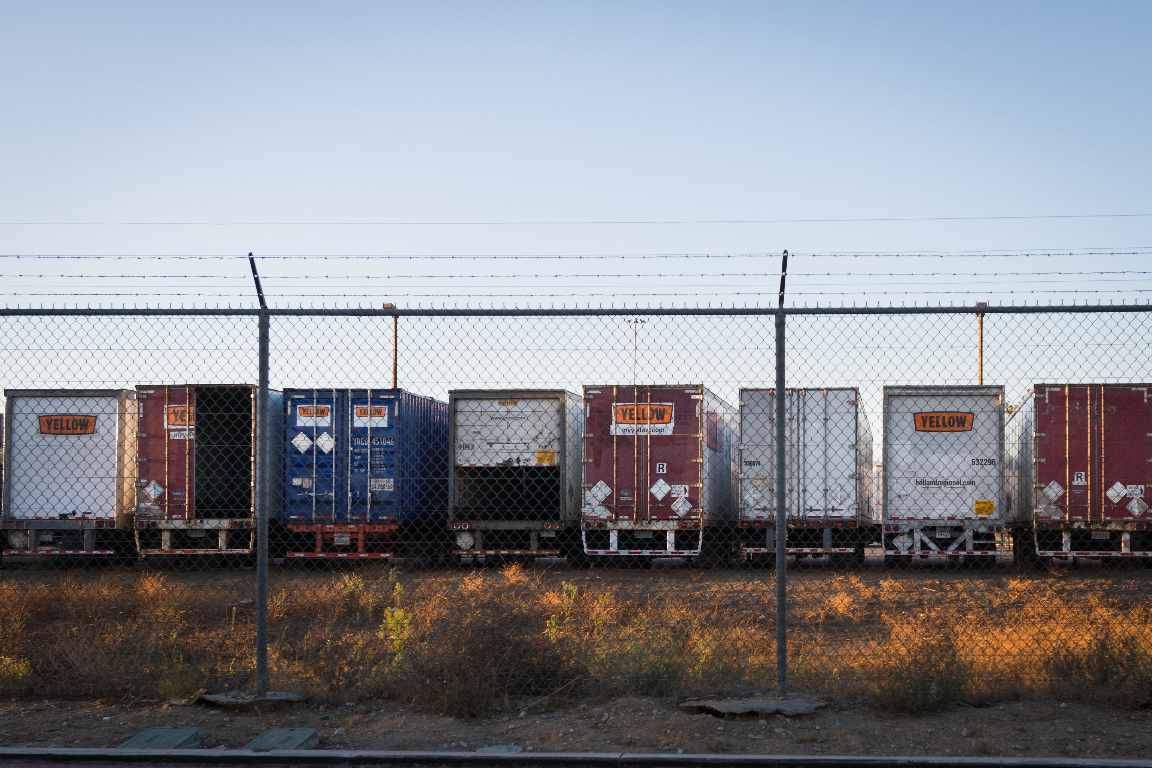 A photo shows a row of parked diesel trucks behind a gate.